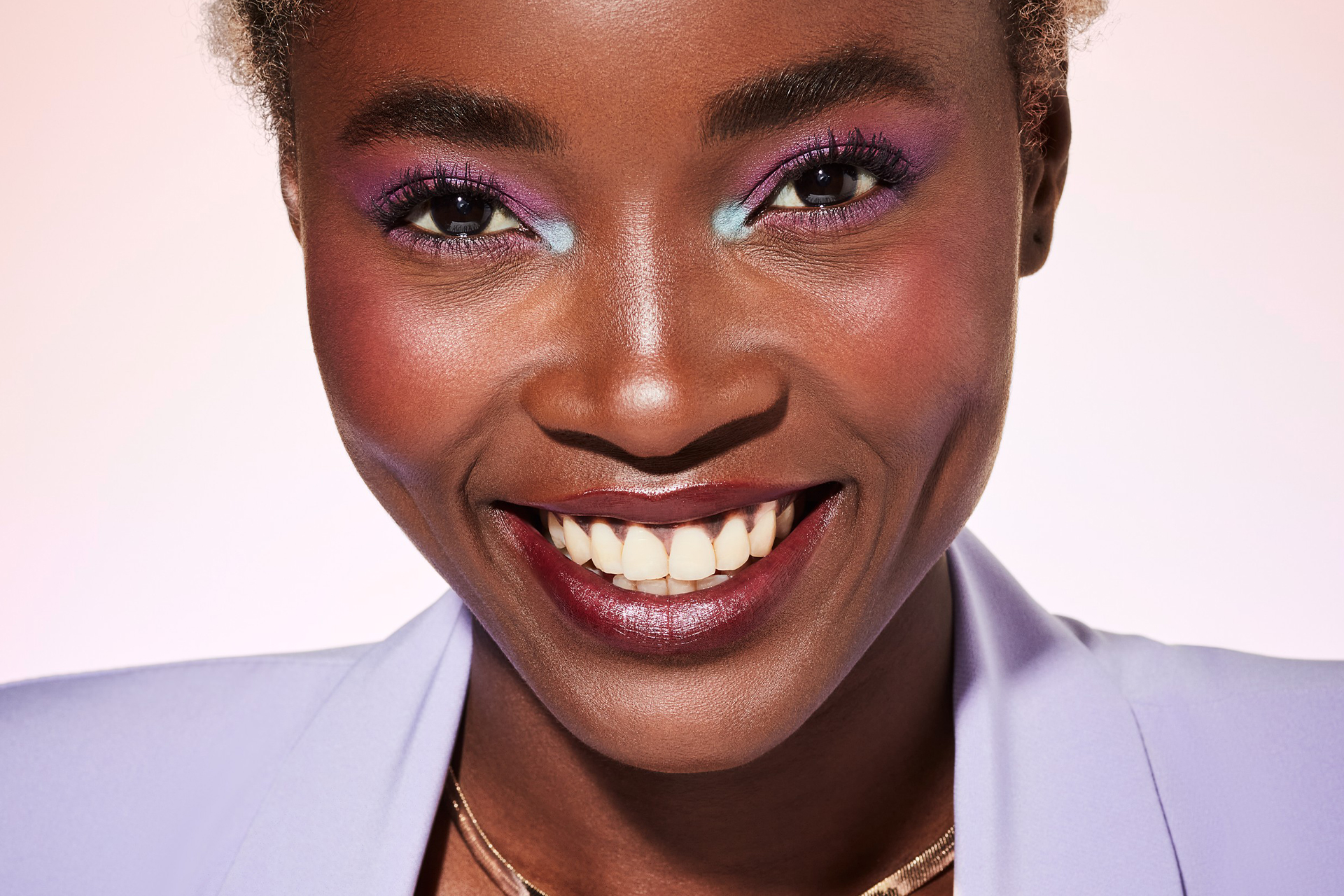 Makeup-beautyvisual-woman-smiling-facing-camera-pastel-look-purple-blazer-102023-Web-Rendition