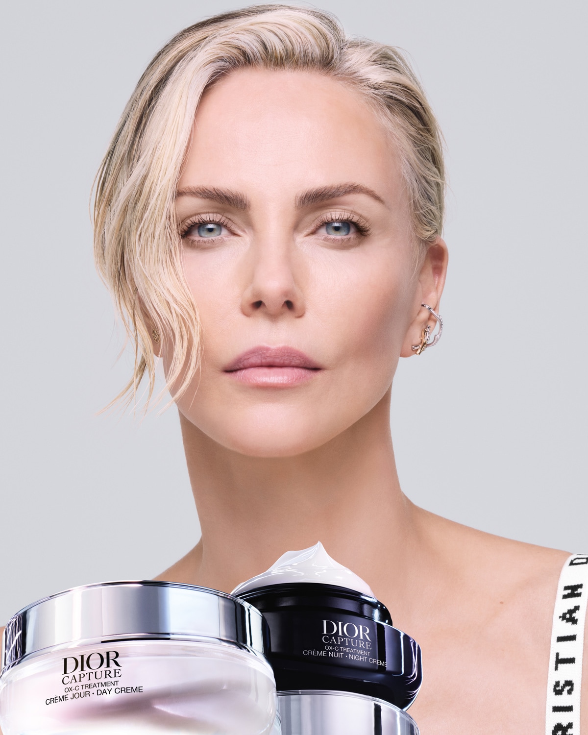 Here's Charlize Theron showcasing Dior Capture OX-C Treatment day and night creams, with the night cream topped with white cream.