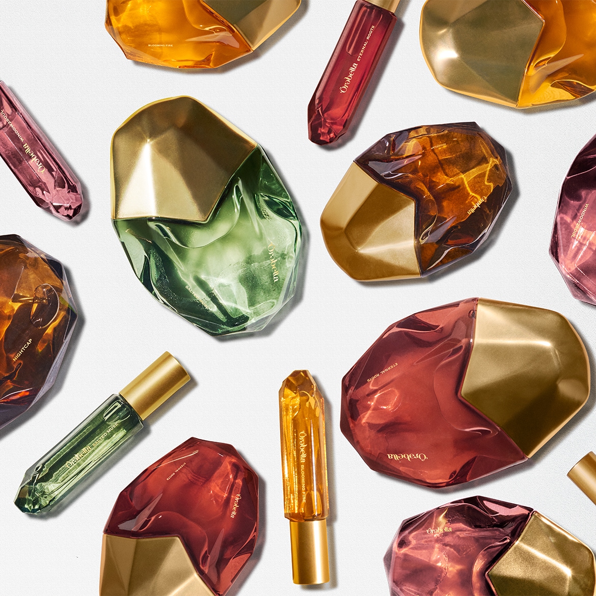 Představujeme sadu parfémů Örabella v různých barvách a tvarech, včetně zelené, červené, oranžové a růžové, s názvy jako Eternal Roots, Blooming Fire a Salted Muse.