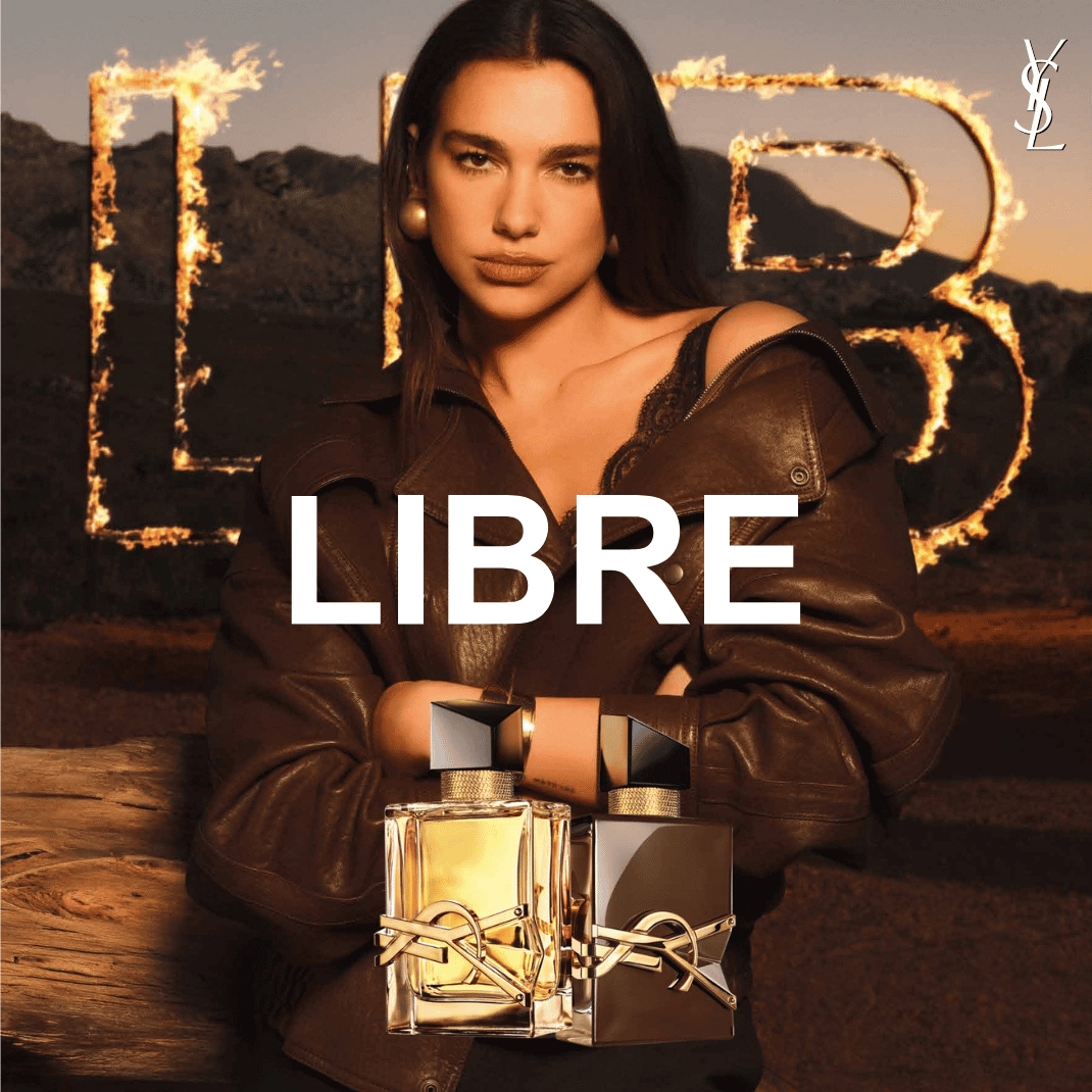 Dua Lipa představuje parfém Libre od Yves Saint Laurent, s nápisem "LIBRE" v popředí a dvěma flakony parfému, jedním zlatým a druhým tmavým, v popředí.