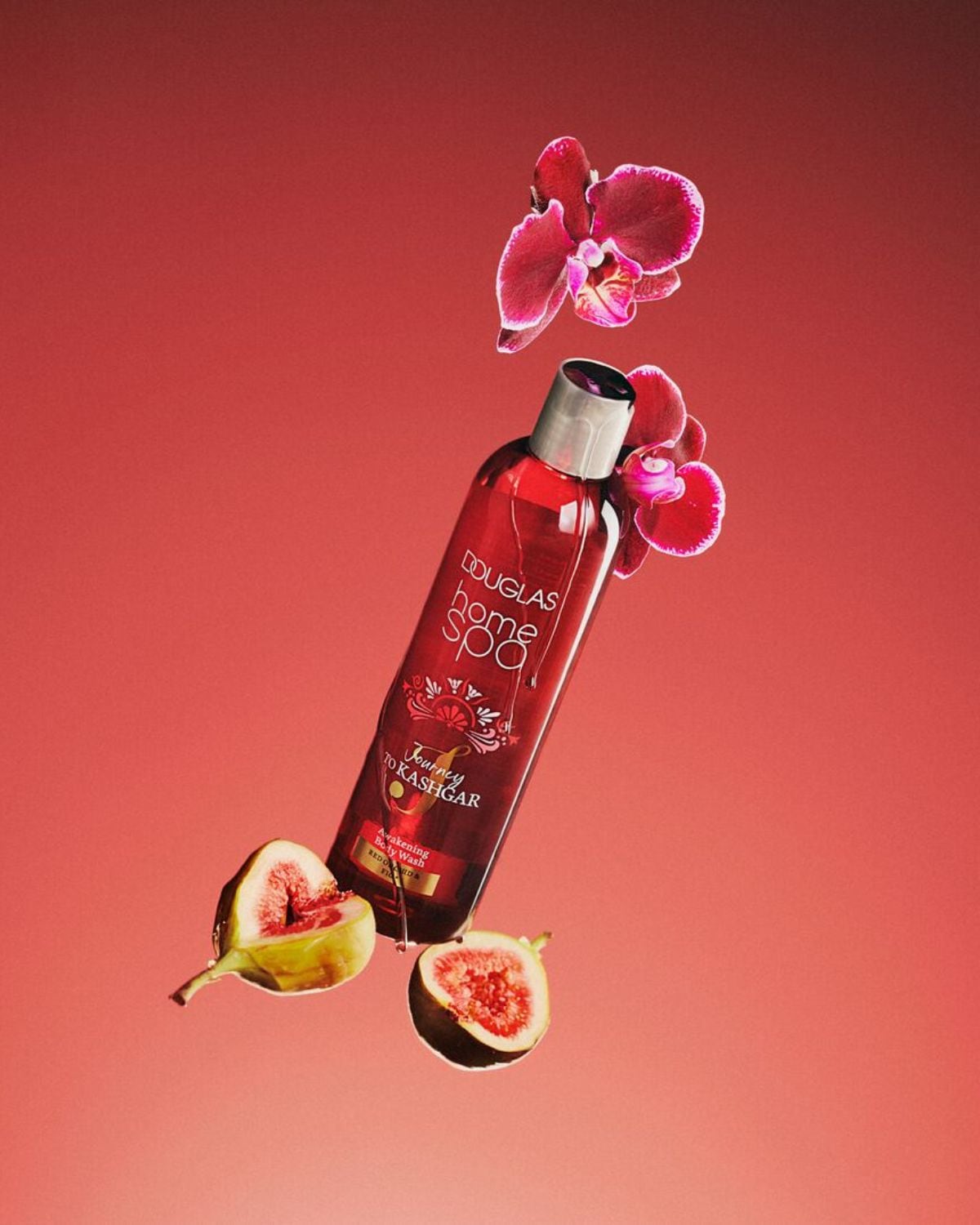 Červená láhev sprchového gelu Douglas Home Spa Journey to Kashgar s fialovými květy a fíky na červeném pozadí.